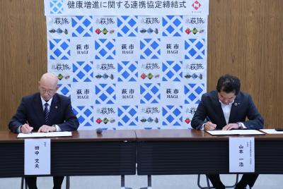 協定書に署名する田中市長(左)と山本一浩支社長(右)